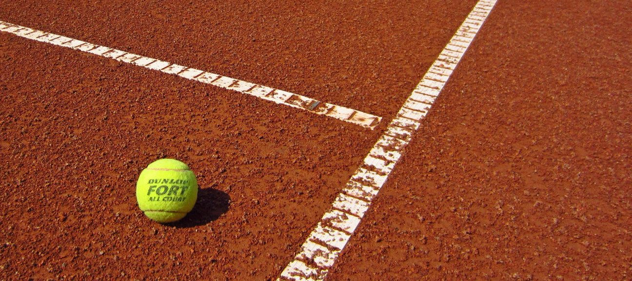 tennis ball sitting on a clay court tennis court